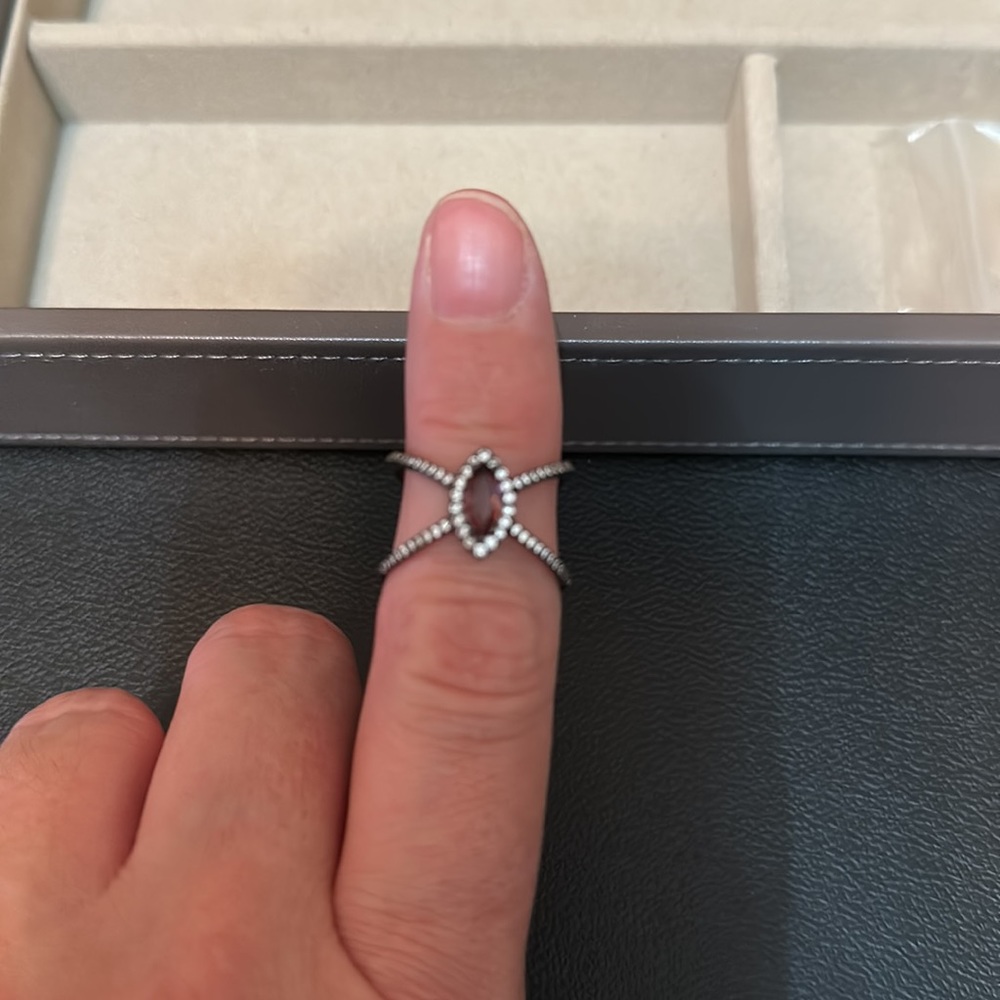 Purple marquee shaped stone, black metal with with clear stone around